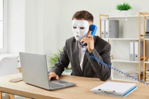 Uomo con maschera al telefono davanti al PC