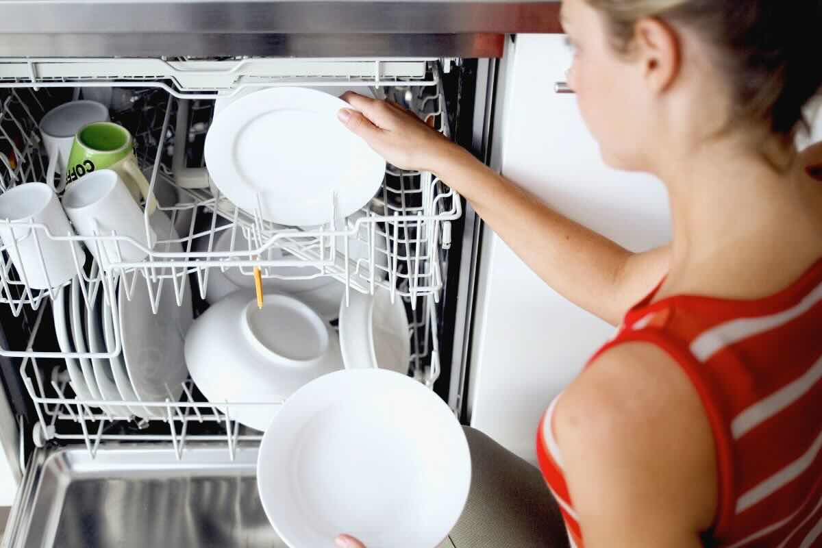 Donna mette piatti nella lavastoviglie