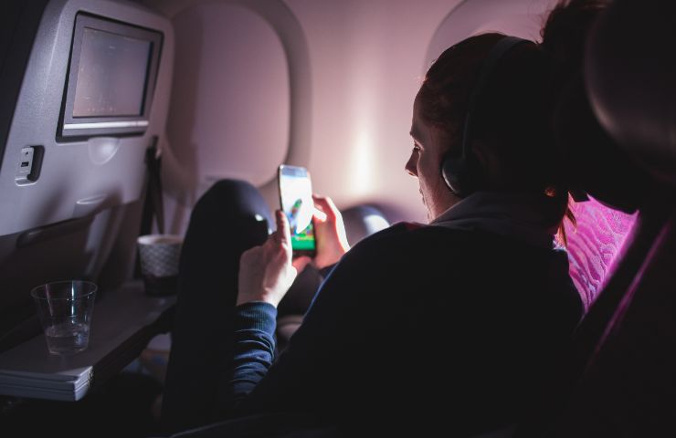 donna che guarda cellulare su aereo