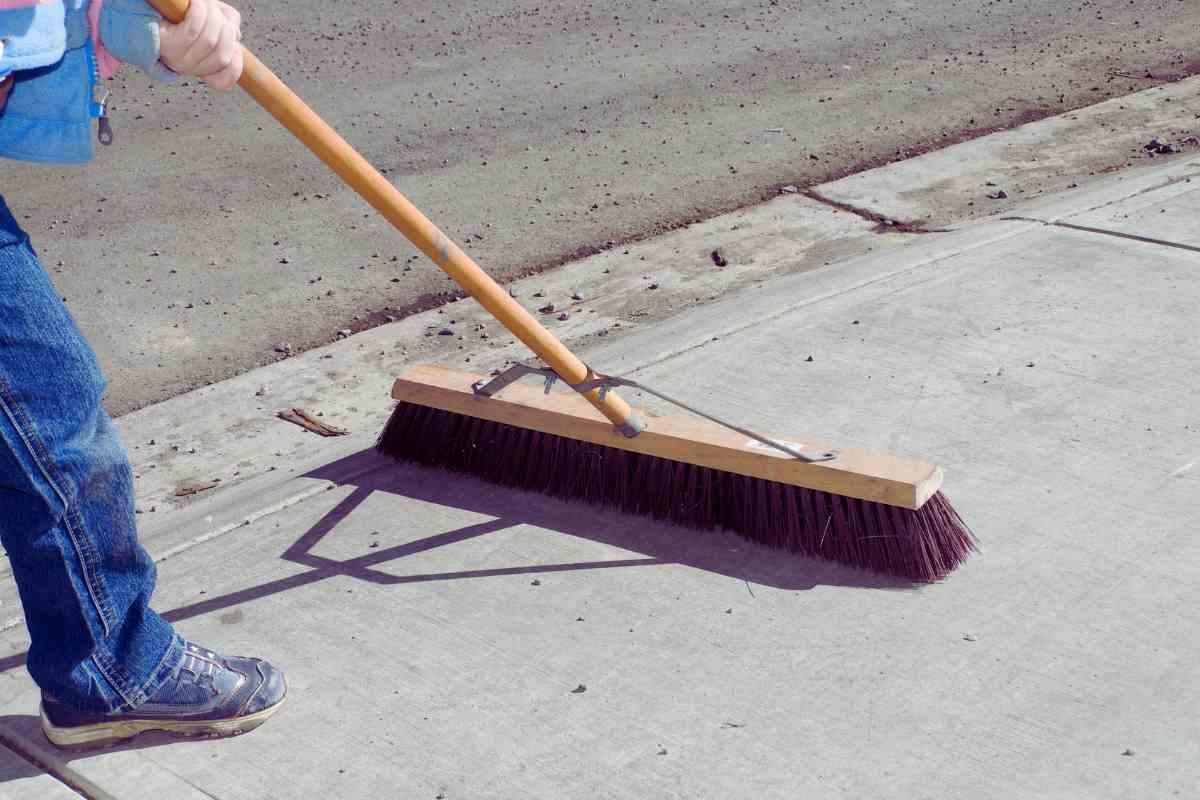 persona che spazza su un marciapiede