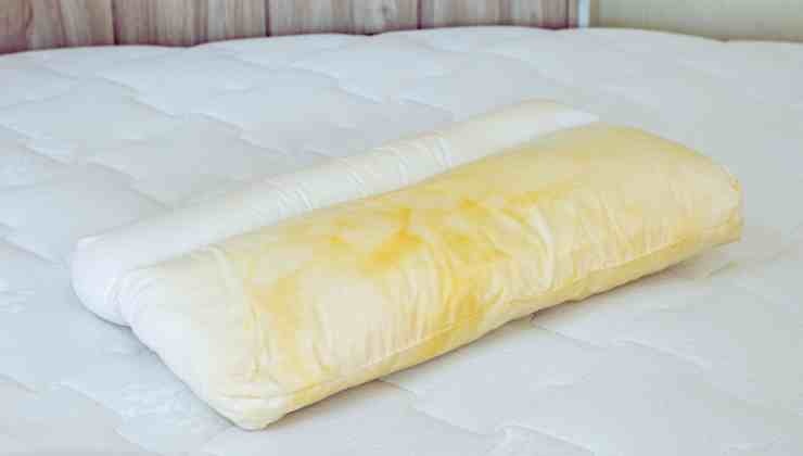 cuscino sporco ingiallito su letto