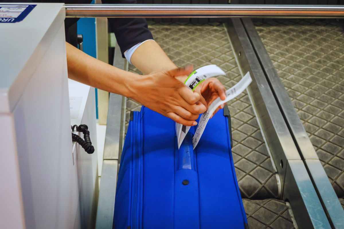 hostess che mette etichetta in bagaglio posto su nastro trasportatore