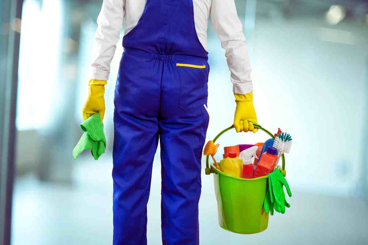 uomo con secchio e guanti e prodotti per pulizie