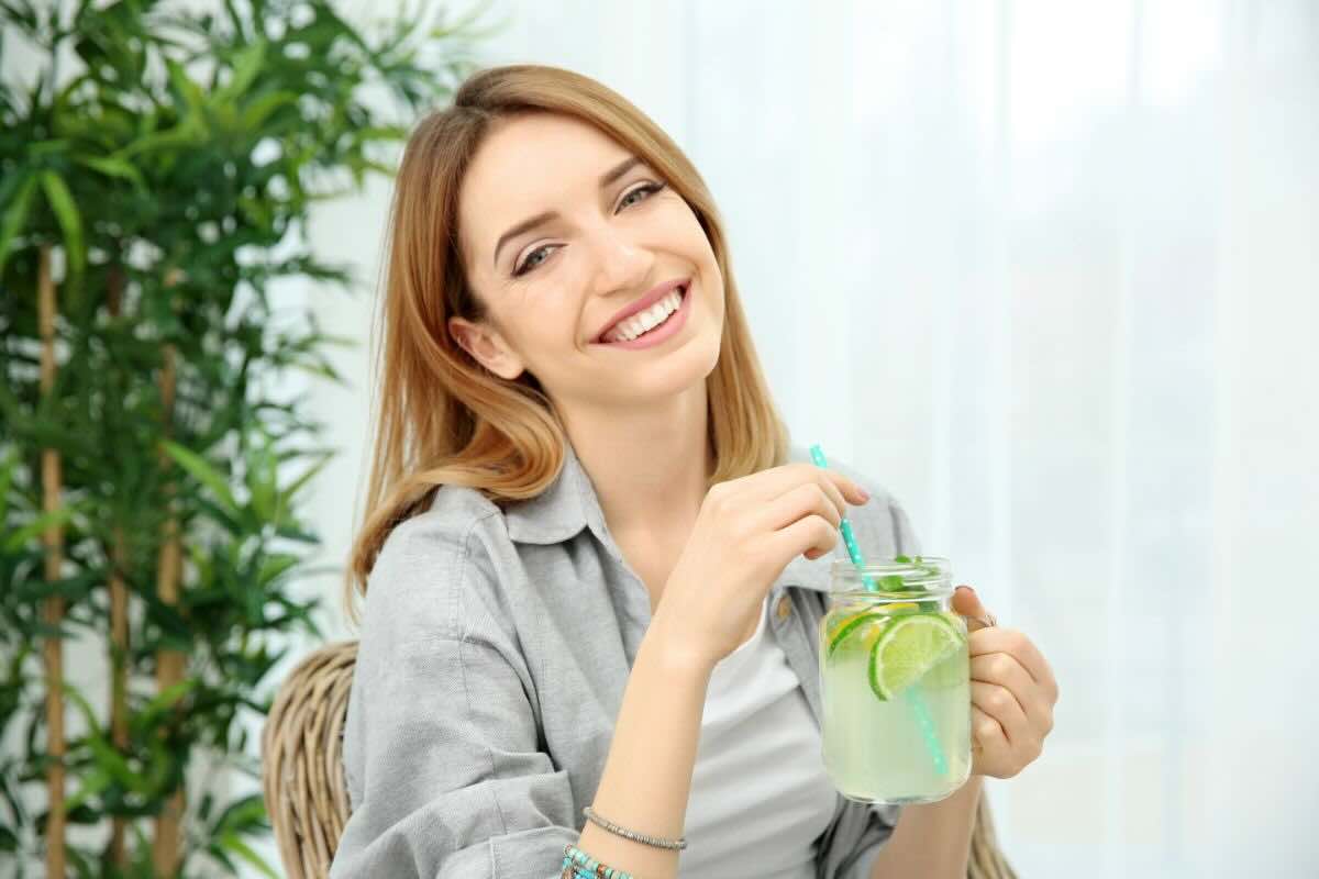 Donna con bicchiere con acqua e fette di limone