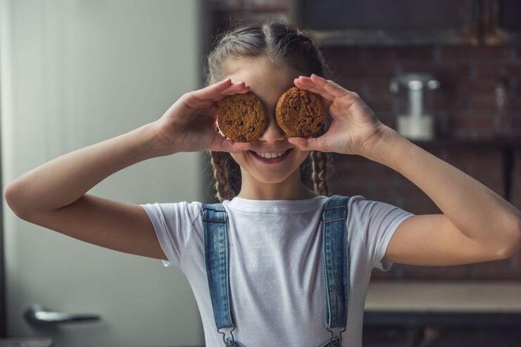 Bambina con biscotti sugli occhi