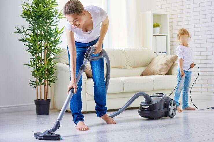 Mamma e figlia con aspirapolvere 
