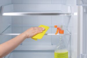 mano che pulisce interno del frigo