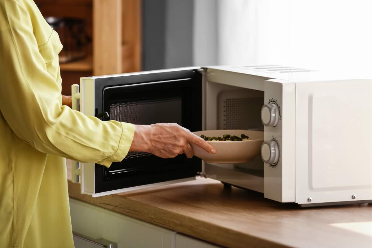 donna che mette piatto nel microonde