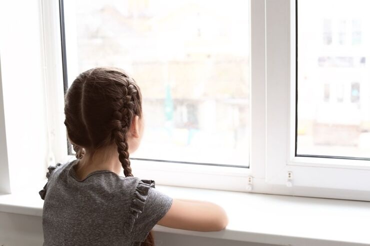 Bambina guarda fuori dalla finestra 