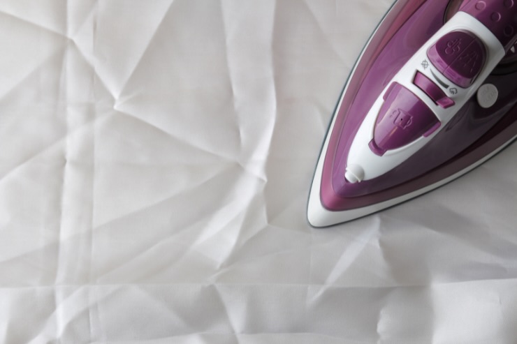 ferro da stiro viola su indumento bianco