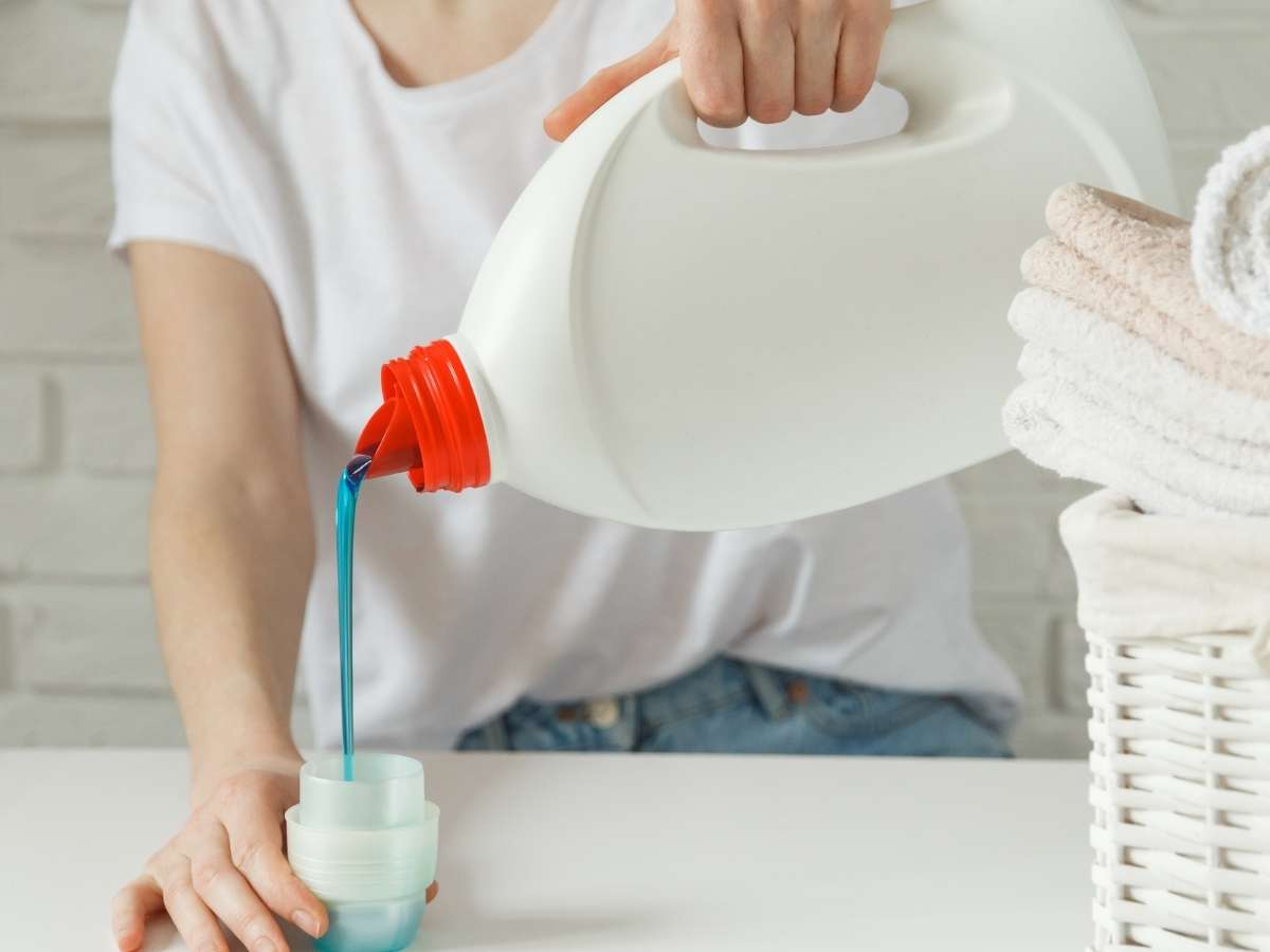 primo piano di donna che versa detersivo per bucato