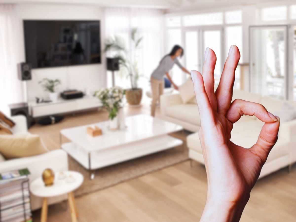 donna che riordina casa sullo sfondo, mano ok in primo piano