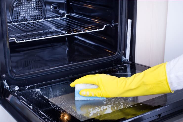 mano che pulisce vetro del forno