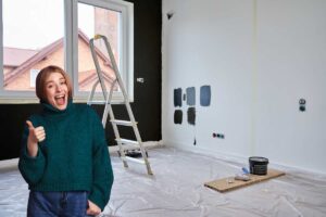 donna con pollice in su, casa con scala per pitturare pareti