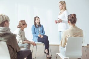Donne riunite in cerchio sedute, una in piedi parla