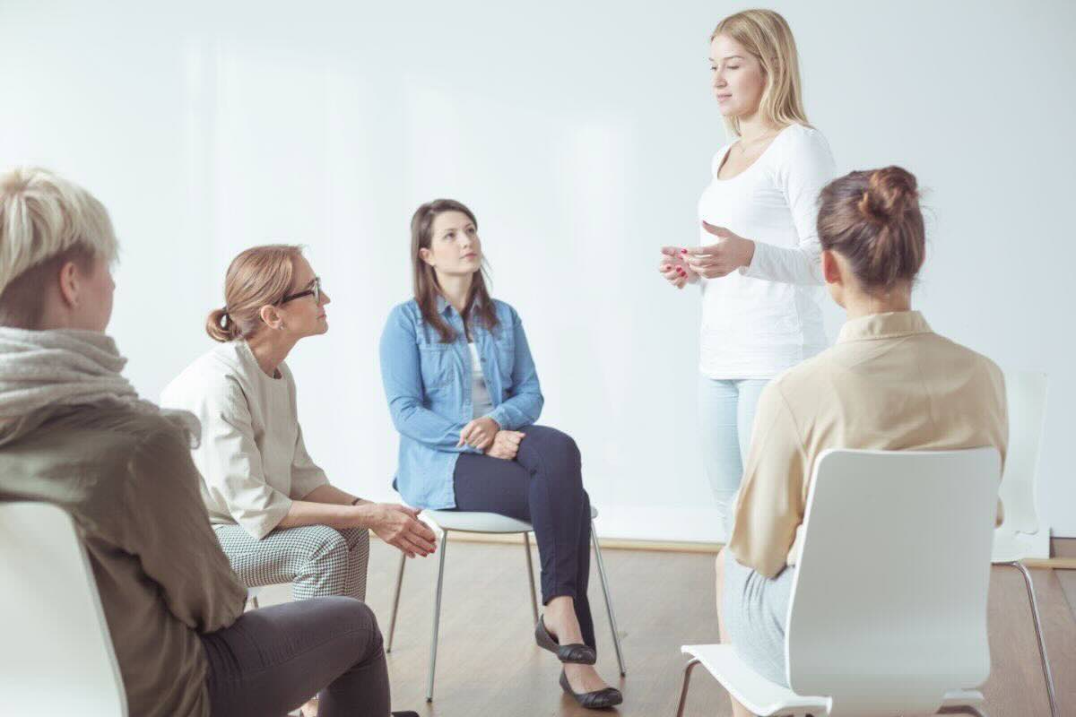 Donne riunite in cerchio sedute, una in piedi parla