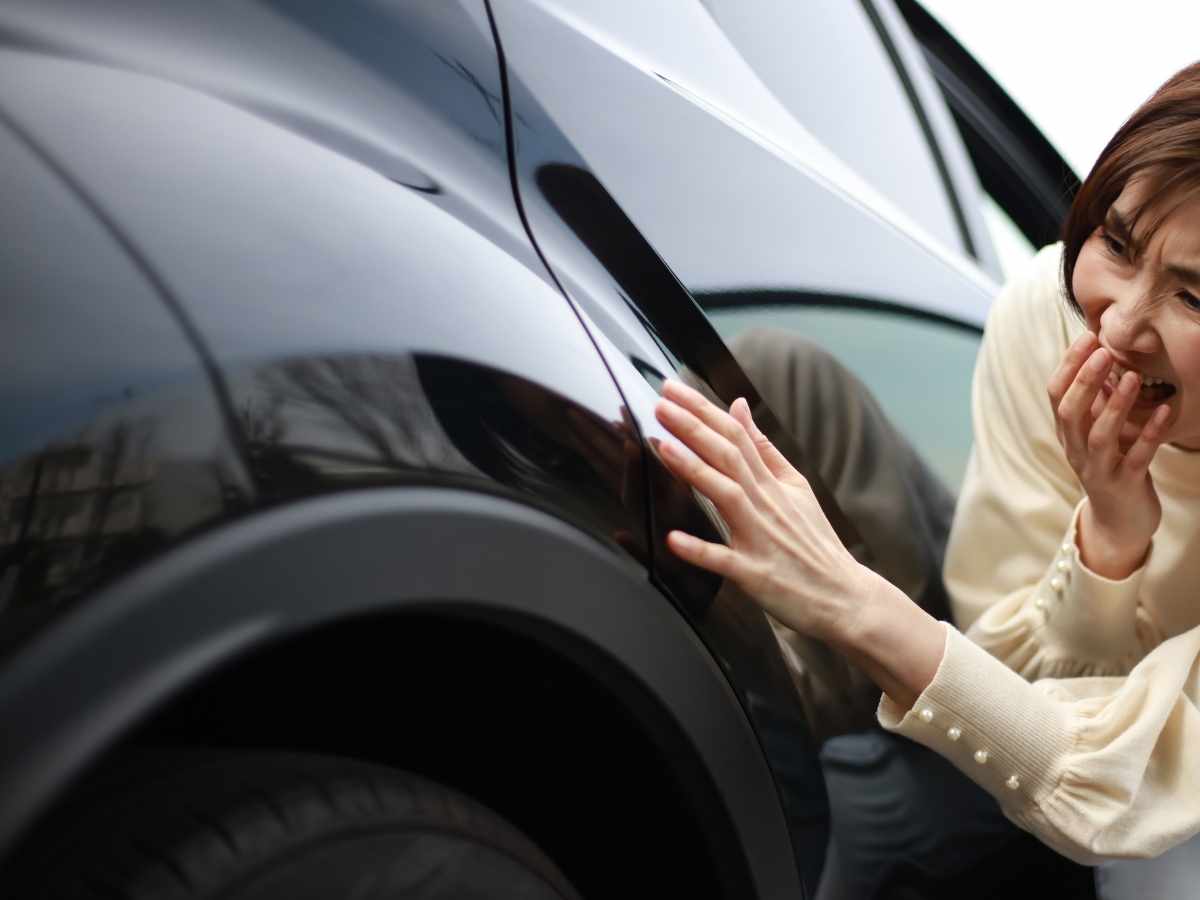 donna che osserva preoccupata la carrozzeria dell'auto